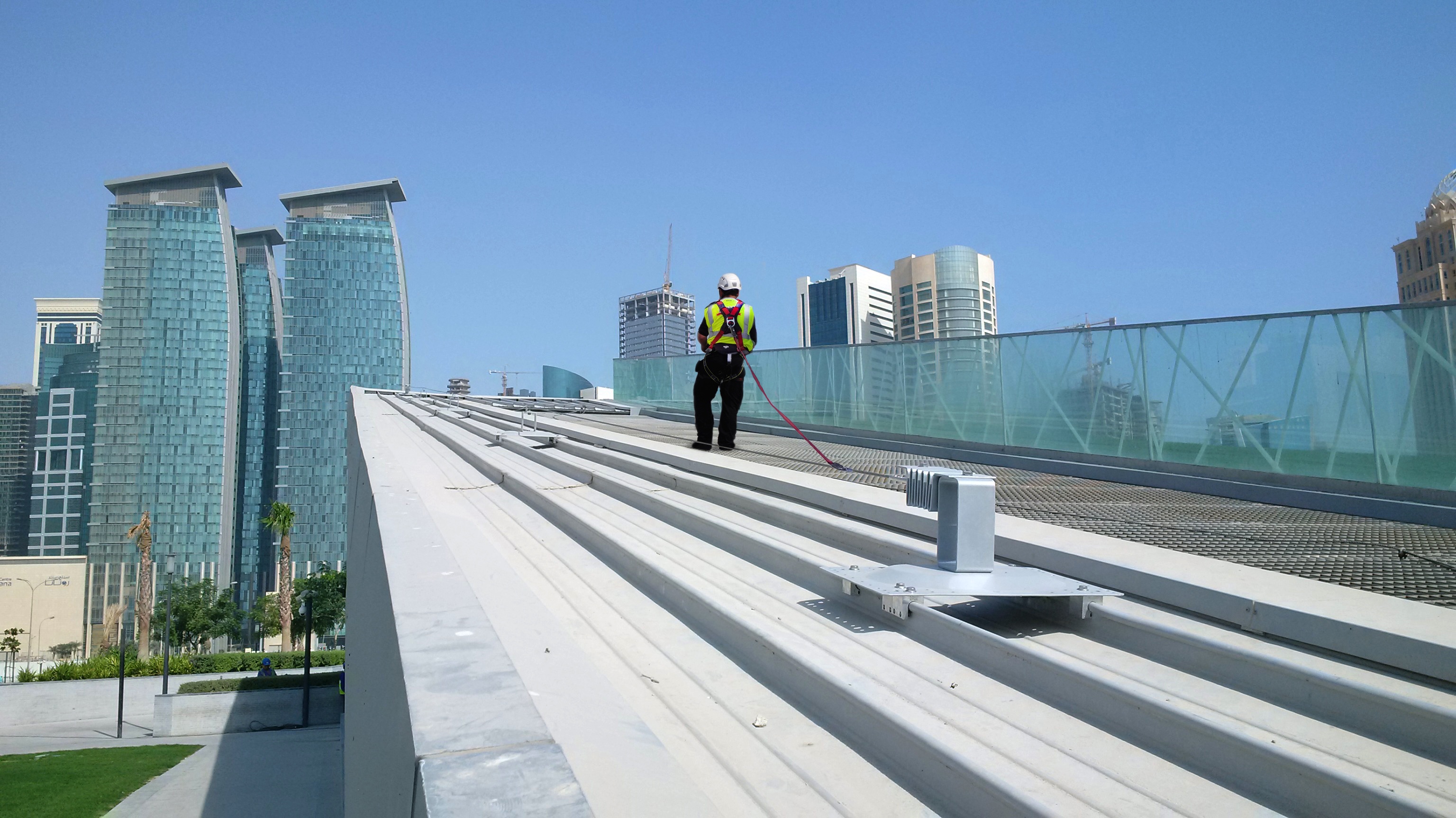 Roofer wearing fall protection harness on a roof